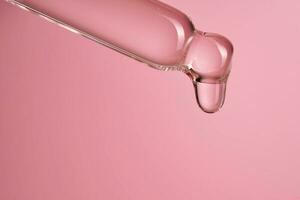 Dropper with serum or cosmetic oil on a pink background. photo