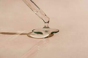 A drop of cosmetic oil falls from the pipette photo