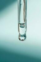 A drop of cosmetic oil falls from the pipette photo