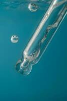 Pipette with cosmetic product in water with bubbles. photo