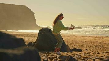 a menina toques a areia em a praia, a areia derrama Fora do dela mãos. video