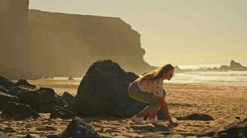 el niña toques el arena en el playa, el arena vierte fuera de su manos. video