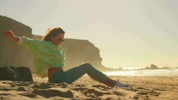 un niña olas su mano sentado en el arena, un salvaje playa video