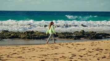 a menina anda em contra a fundo do a ondas, a enfurecido oceano, a pôr do sol video