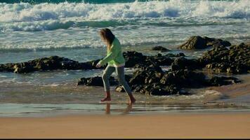 de meisje wandelingen tegen de achtergrond van de golven, de woedend oceaan, de zonsondergang video