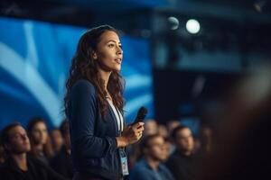 young woman giving a talk at a conference in a bright stage with photo