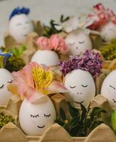 A egg with a face on it sits in a white egg holder with flowers on it. photo