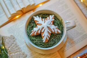 nuevo años decoración con un libro, un taza de té, galletas y Navidad árbol detalles foto