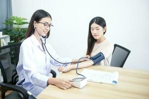 Asian female doctor with blood pressure monitor of female patient at hospital concept for health care and people photo