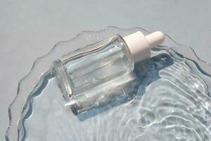 A bottle of serum in water on a blue background. photo