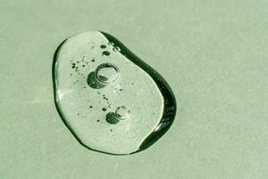 A drop of transparent cosmetic gel on a green background. photo