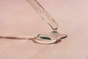 A drop of cosmetic oil falls from the pipette photo