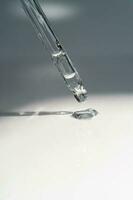 A drop of cosmetic oil falls from the pipette photo