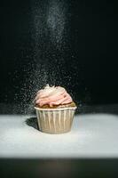 Cupcake on a dark background, which is sprinkled on top. photo