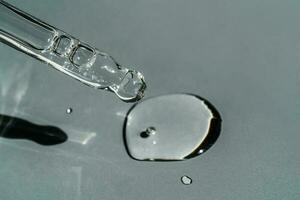 A drop of cosmetic oil falls from the pipette photo