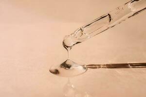 A drop of cosmetic oil falls from the pipette photo