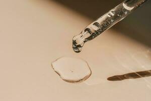 A drop of cosmetic oil falls from the pipette photo