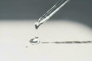 A drop of cosmetic oil falls from the pipette photo