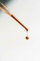 A drop of foundation drips from the pipette. photo