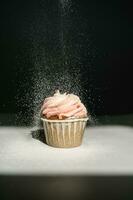 Cupcake on a dark background, which is sprinkled on top. photo