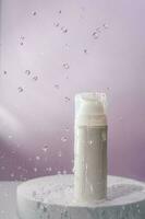 Cosmetic bottle with water splashes on a purple background. photo