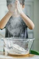 The child cooks in the kitchen. Sifts the flour. photo