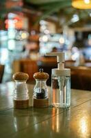 un sal y pimienta criba vibradora y un antiséptico estar en el mesa en un bar o cafetería. foto