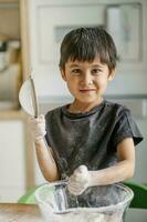 The child cooks in the kitchen. Sifts the flour. photo