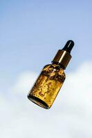 A brown bottle of serum against the sky. photo