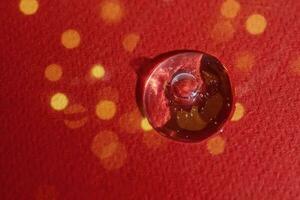 A drop of serum on a red background with bokeh. photo