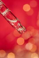 Pipette with serum on a red holiday background with bokeh. photo