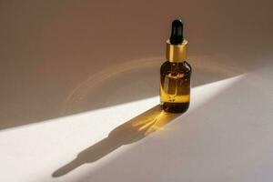 A brown bottle of serum against the beige background.. photo