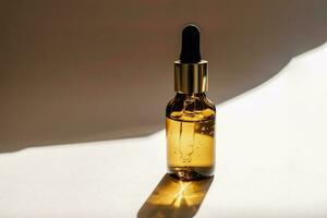 A brown bottle of serum against the beige background.. photo