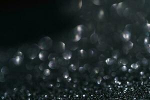 Black abstract glitter background with shiny bokeh photo
