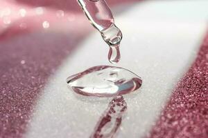 Cosmetic pipette with a pink on dark background. photo