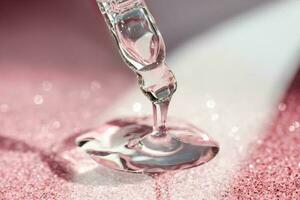 Cosmetic pipette with a pink on dark background. photo