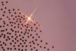Abstract pink background with sparkles in the shape of stars. photo