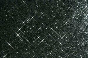 Abstract black background with sparkles in the shape of stars. photo