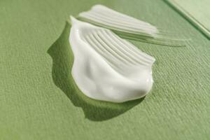 The texture of the white cream on a green background. photo