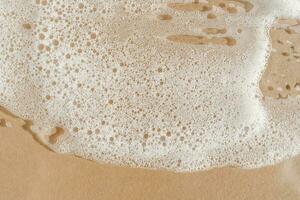 Texture of white foam on a beige background. photo