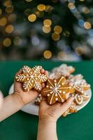 Ginger Christmas cookies in children's hands on the background of the Christmas tree. photo