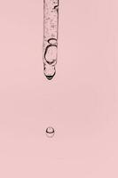 transparente pipeta con productos cosméticos en un rosado antecedentes. foto
