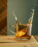 Transparent mug with tea and splashes on a green background. photo