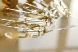 Pipettes with oil or serum on a golden background. photo