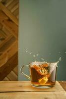 Transparent mug with tea and splashes on a green background. photo