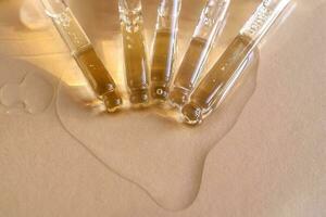 Pipettes with oil or serum on a golden background. photo