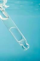 Pipette with cosmetic product in water with bubbles. photo