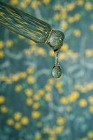 A dripping pipette with a drop of cosmetics gel. photo