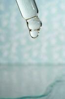 A dripping pipette with a drop of cosmetics gel. photo