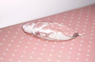 Transparent hyaluronic gel on a pink polka dots background. photo